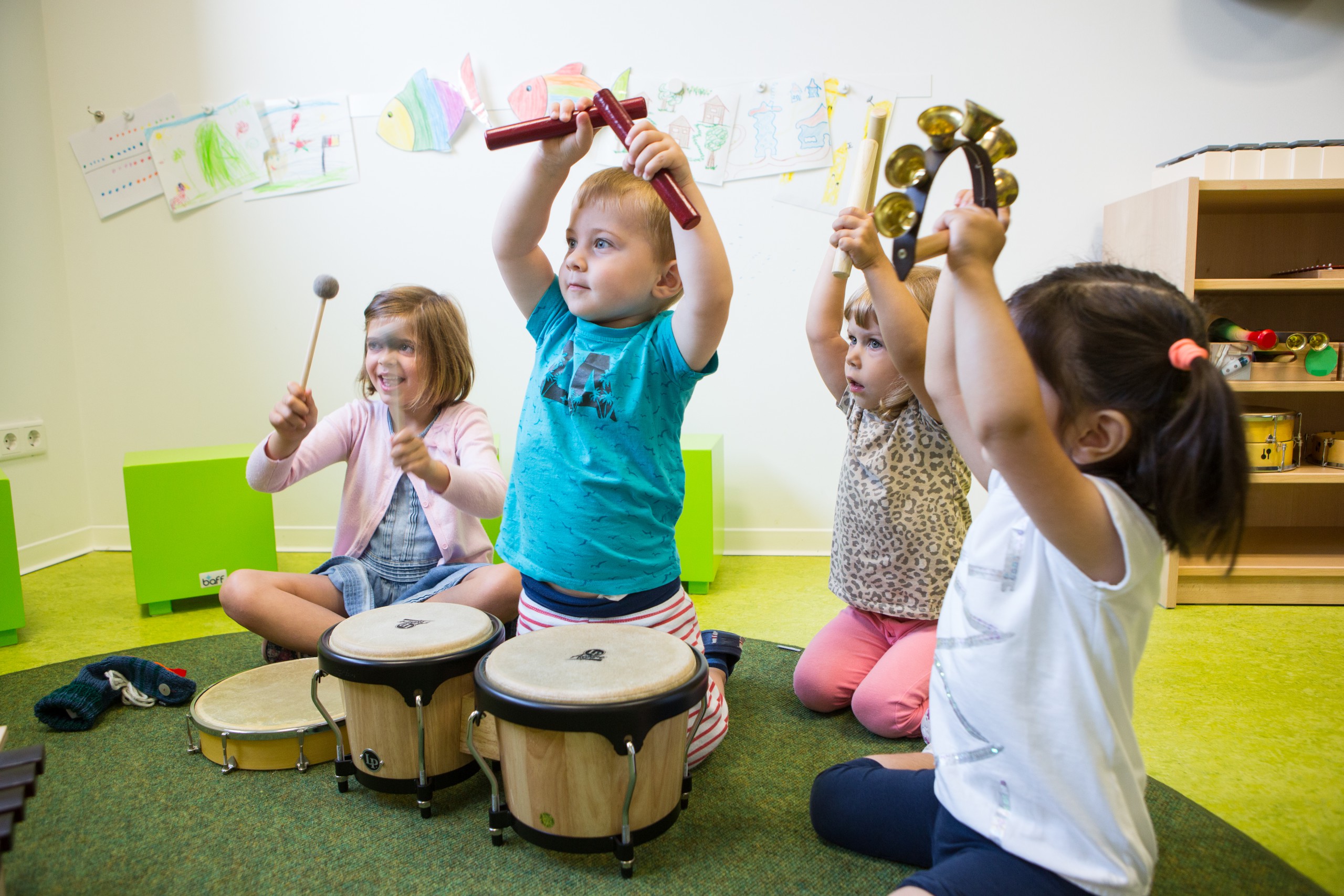Kinder musizieren mit Schellenkranz, Trommeln und Klanghölzern