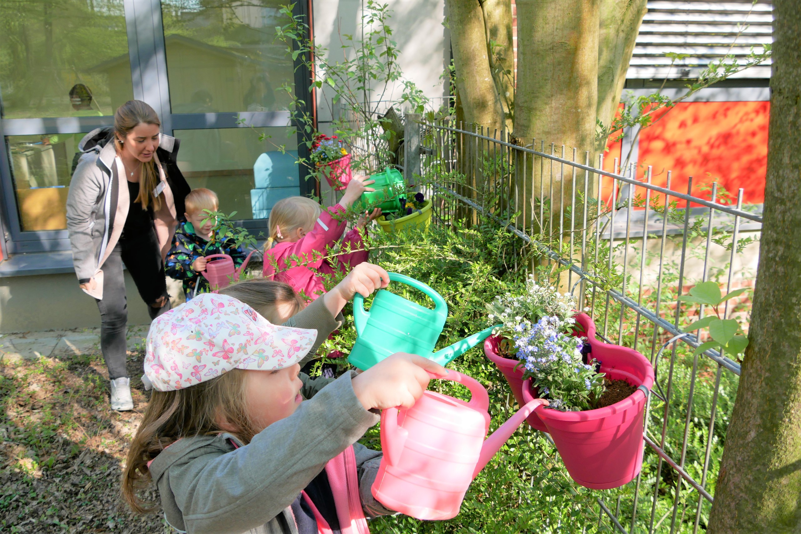 Kinder gießen im Garten die Blumen